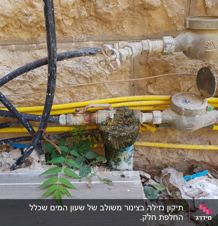צינורות מים וברזים על קיר אבן